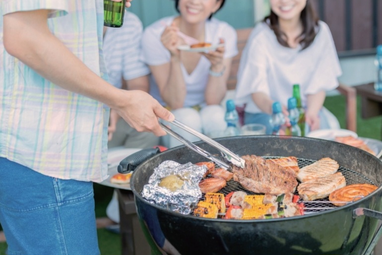 屋外でBBQを楽しんでいる人たち