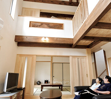 新古今 自然素材住宅の吹き抜けリビング、木製扉と木の梁の室内